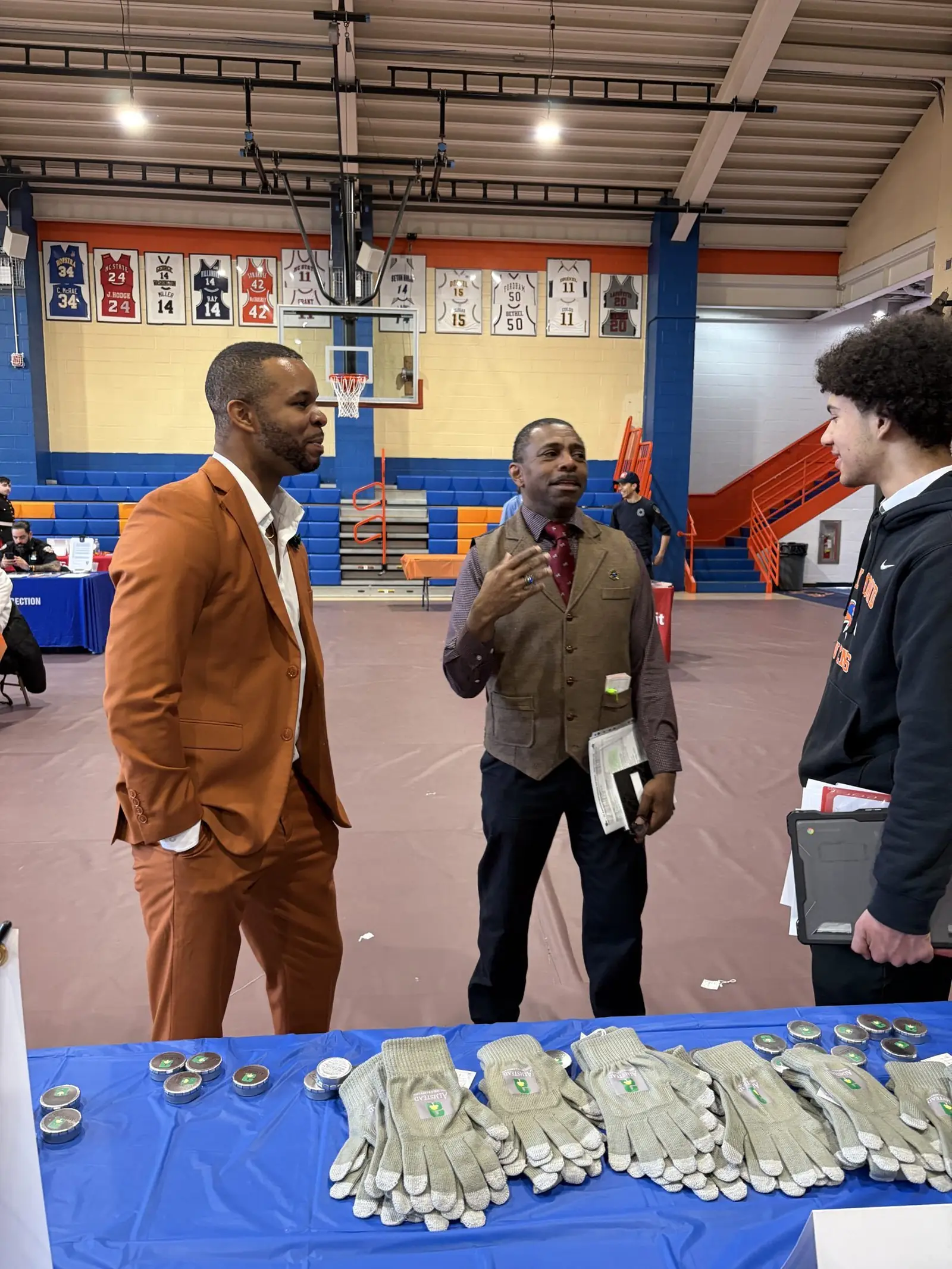 Merrick Lee Jr. in conversation with a teacher and a student in the school gym