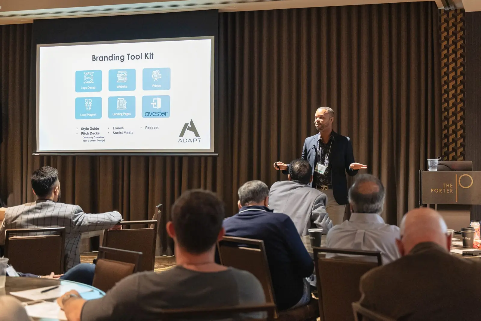 Merrick Lee speaking on stage in front of a branding tool kit slide